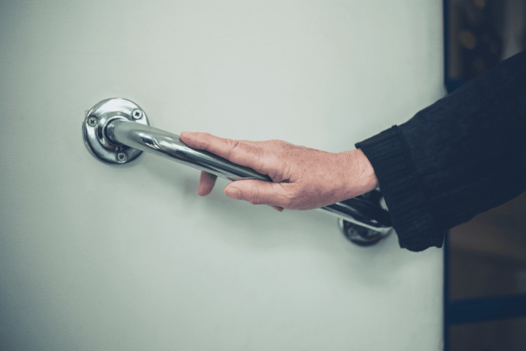 an elder guy holding a grab bar to support himself