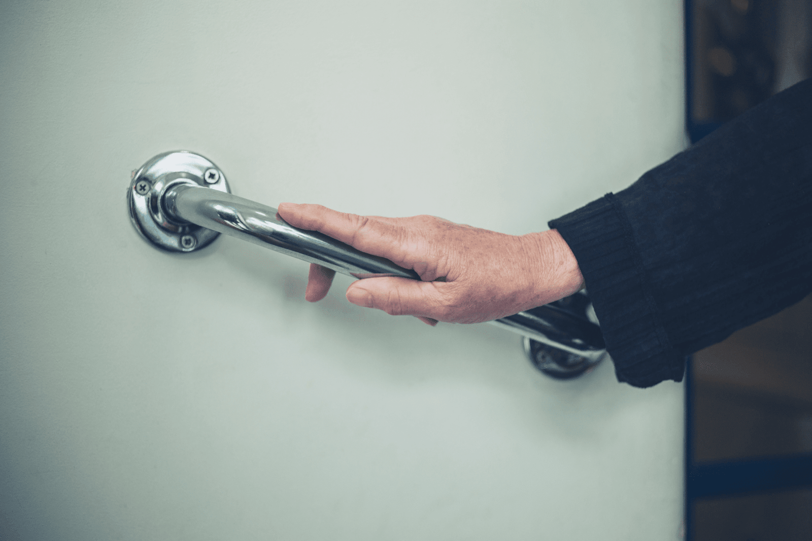an elder guy holding a grab bar to support himself