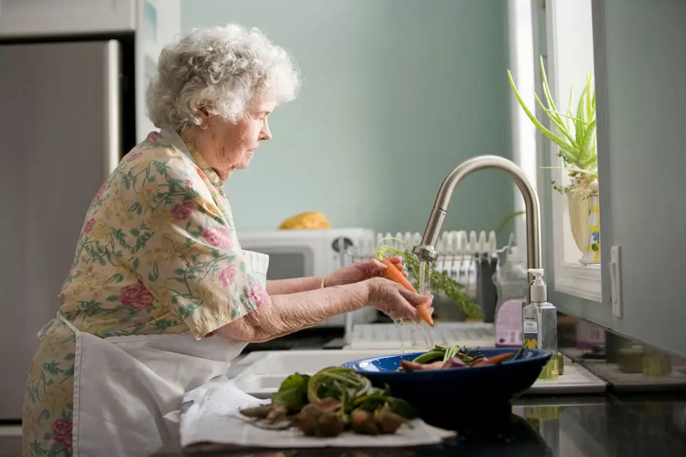 An elderly washing vegetables